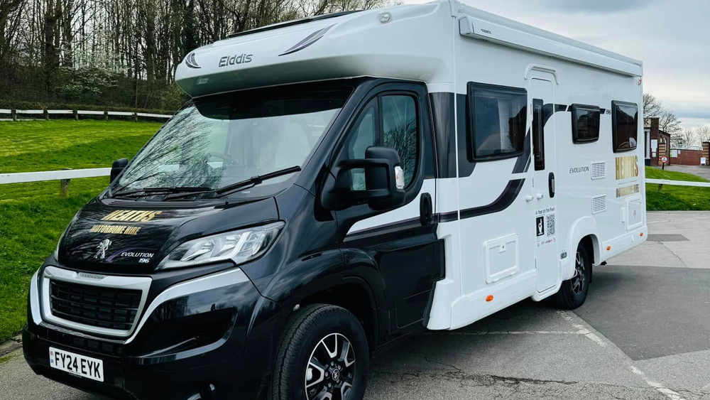 Dark grey Elddis Evolution motorhome from Heaths Motorhome Hire parked on green grass on a sunny day
