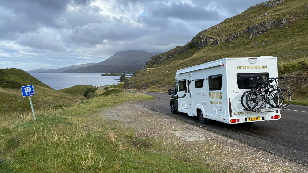 Heaths Motorhome Hire motorhome parked on a Highland road beside a loch with mountains in the background
