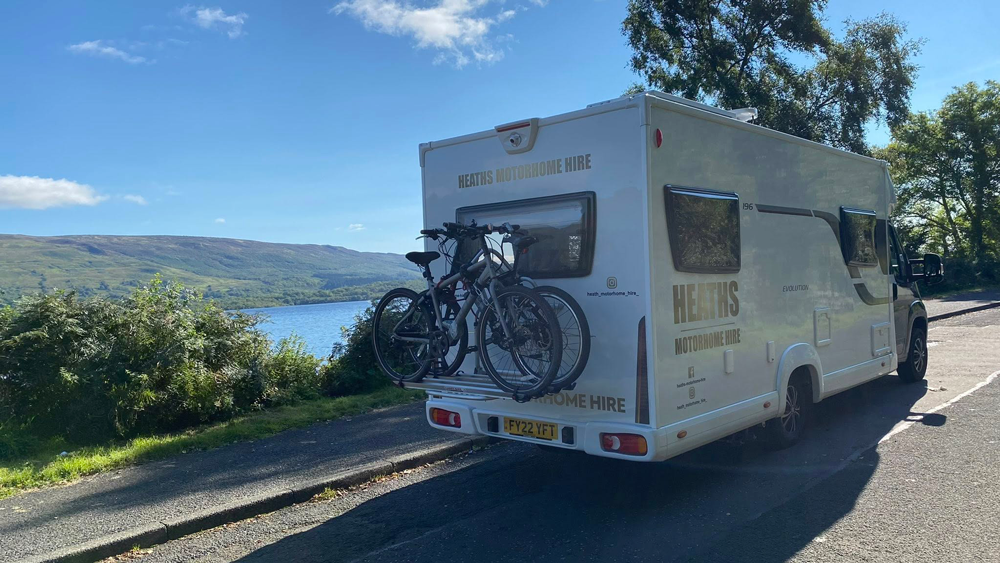 Motorhome with bike rack driving along a lakeside road in the Scottish Highlands
